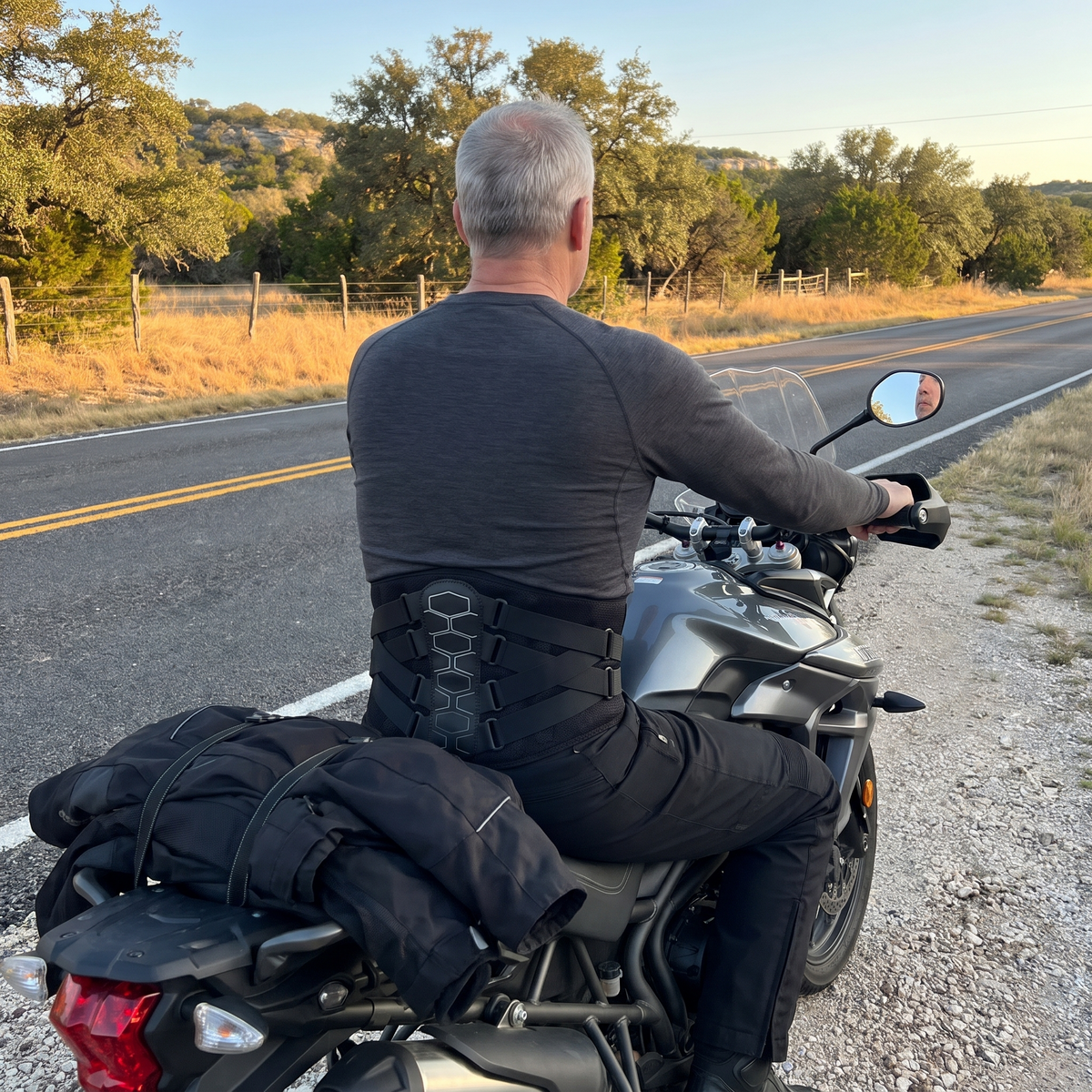 Rider wearing MotoSupport over his base layer, sitting on his motorcycle at the roadside